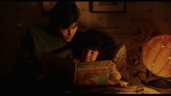 Movie still from “While You Were Sleeping” (1995), directed by Jon Turteltaub – A man and a little girl are reading a book together; Medium shot, High angle