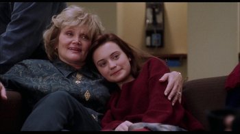 Movie still from “While You Were Sleeping” (1995), directed by Jon Turteltaub – A woman sitting next to a young girl on a couch; Medium shot, High angle