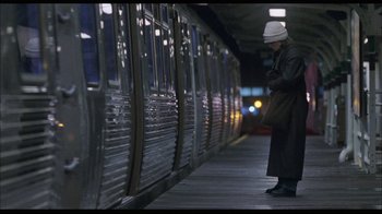 Movie still from “While You Were Sleeping” (1995), directed by Jon Turteltaub – A man standing on a train platform next to a train; Wide shot, Low angle