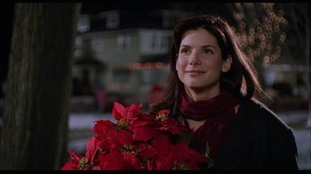 Movie still from “While You Were Sleeping” (1995), directed by Jon Turteltaub – A woman holding a bouquet of poinsettias in her hands; Close Up shot, Over the shoulder angle
