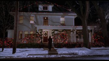 Movie still from “While You Were Sleeping” (1995), directed by Jon Turteltaub – A person standing in front of a house with christmas lights on it; Extreme Wide shot, Low angle