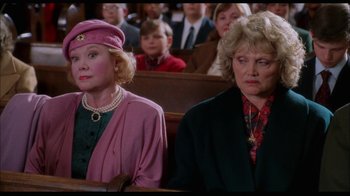 Movie still from “While You Were Sleeping” (1995), directed by Jon Turteltaub – Two women sitting next to each other in front of a group of people; Close Up shot, High angle