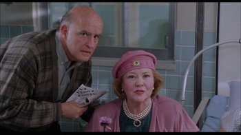 Movie still from “While You Were Sleeping” (1995), directed by Jon Turteltaub – An older woman in a pink hat is sitting next to an older man in a green shirt; Medium shot, Low angle