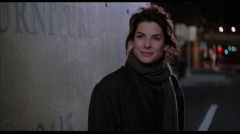 Movie still from “While You Were Sleeping” (1995), directed by Jon Turteltaub – A woman wearing a black coat and a gray scarf; Close Up shot, Over the shoulder angle