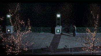 Movie still from “While You Were Sleeping” (1995), directed by Jon Turteltaub – A man standing in front of a clock at night; Extreme Wide shot, High angle