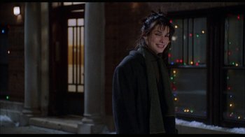 Movie still from “While You Were Sleeping” (1995), directed by Jon Turteltaub – A woman smiling while standing in front of christmas lights; Medium shot, Over the shoulder angle