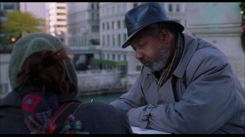 Movie still from “While You Were Sleeping” (1995), directed by Jon Turteltaub – An older man sitting at a table writing on a piece of paper; Medium shot, Over the shoulder angle
