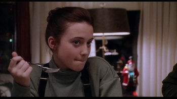 Movie still from “While You Were Sleeping” (1995), directed by Jon Turteltaub – A woman with a fork in her mouth sitting in a room; Close Up shot, Over the shoulder angle