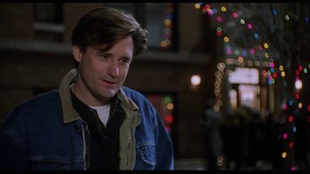 Movie still from “While You Were Sleeping” (1995), directed by Jon Turteltaub – A man in a denim jacket is standing in front of lights; Close Up shot, Over the shoulder angle