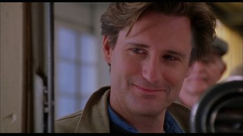 Movie still from “While You Were Sleeping” (1995), directed by Jon Turteltaub – A man smiling for the camera; Close Up shot, Over the shoulder angle