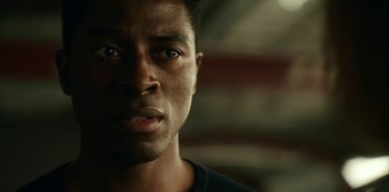 Movie still from “Another Life” (2019), created by Aaron Martin – A man's face in a dark room; Close Up shot, Over the shoulder angle