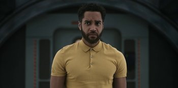 Movie still from “Another Life” (2019), created by Aaron Martin – A man in a yellow shirt is looking at the camera; Medium shot, Low angle