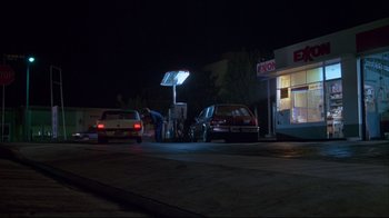 Movie still from “White Dog” (1982), directed by Samuel Fuller – A gas station at night with cars at the pumps; Wide shot, Low angle