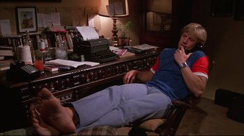 Movie still from “White Dog” (1982), directed by Samuel Fuller – A man sitting on a chair in front of a desk; Medium shot, High angle