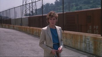 Movie still from “White Dog” (1982), directed by Samuel Fuller – A young man standing on the side of a road holding a tennis racquet; Medium shot, Over the shoulder angle