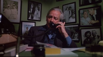 Movie still from “White Dog” (1982), directed by Samuel Fuller – An older man sitting at a table talking on a phone; Medium shot, High angle