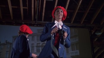 Movie still from “White Dog” (1982), directed by Samuel Fuller – A woman in a blue suit and red hat holding a camera; Medium shot, Low angle