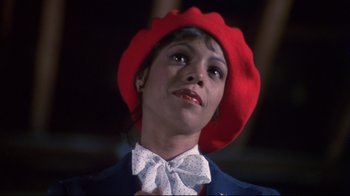 Movie still from “White Dog” (1982), directed by Samuel Fuller – A woman wearing a red hat and a white bow tie; Close Up shot, Low angle