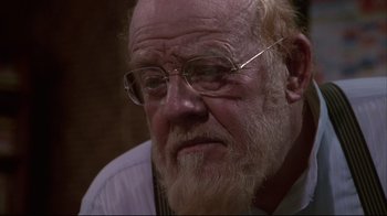 Movie still from “White Dog” (1982), directed by Samuel Fuller – An older man with a beard and glasses; Close Up shot, Over the shoulder angle