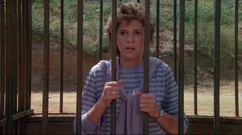 Movie still from “White Dog” (1982), directed by Samuel Fuller – A young woman holding onto a metal fence; Medium shot, High angle
