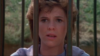 Movie still from “White Dog” (1982), directed by Samuel Fuller – A young woman looking through the bars of a metal fence; Close Up shot, Low angle