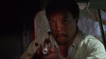 Movie still from “White Dog” (1982), directed by Samuel Fuller – A man holding a gun in a vehicle; Close Up shot, Low angle