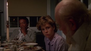 Movie still from “White Dog” (1982), directed by Samuel Fuller – A woman sitting at a dinner table with two men; Close Up shot, Over the shoulder angle