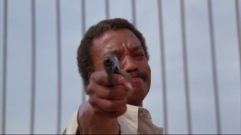 Movie still from “White Dog” (1982), directed by Samuel Fuller – A man holding a gun pointed at the camera; Close Up shot, Low angle