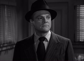 Movie still from “White Heat” (1949), directed by Raoul Walsh – A black and white photo of a man wearing a suit and hat; Close Up shot, Low angle