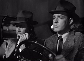 Movie still from “White Heat” (1949), directed by Raoul Walsh – Two men in suits and hats are sitting in a car; Close Up shot, Low angle