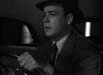 Movie still from “White Heat” (1949), directed by Raoul Walsh – A black and white photo of a man driving a car; Close Up shot, Low angle