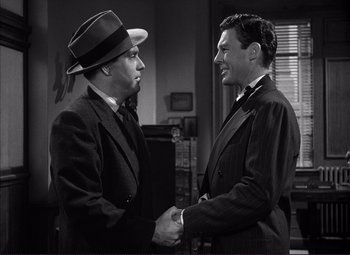 Movie still from “White Heat” (1949), directed by Raoul Walsh – A black and white photo of two men shaking hands; Medium shot, Over the shoulder angle