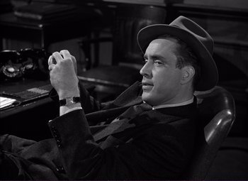 Movie still from “White Heat” (1949), directed by Raoul Walsh – A black and white photo of a man wearing a hat; Medium shot, High angle