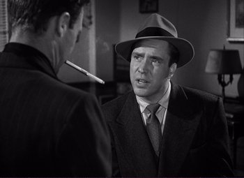 Movie still from “White Heat” (1949), directed by Raoul Walsh – A man wearing a suit and a hat talking to another man; Close Up shot, Over the shoulder angle