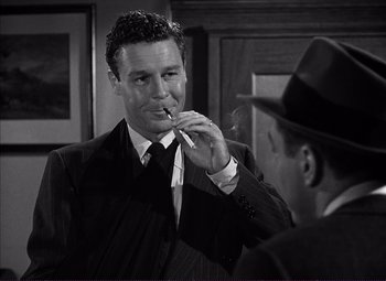 Movie still from “White Heat” (1949), directed by Raoul Walsh – A man in a suit and tie smoking a cigarette; Close Up shot, Over the shoulder angle