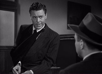 Movie still from “White Heat” (1949), directed by Raoul Walsh – A man wearing a suit and tie talking to another man wearing a hat; Close Up shot, Over the shoulder angle