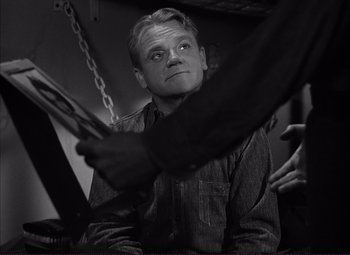 Movie still from “White Heat” (1949), directed by Raoul Walsh – A black - and - white photo of a man holding a chain; Medium shot, Over the shoulder angle