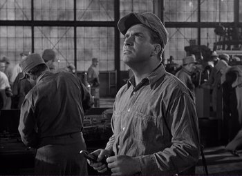 Movie still from “White Heat” (1949), directed by Raoul Walsh – A man holding a wrench in a factory; Medium shot, Low angle