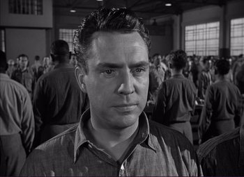 Movie still from “White Heat” (1949), directed by Raoul Walsh – A man standing in front of a group of people; Close Up shot, Low angle