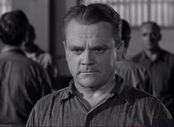 Movie still from “White Heat” (1949), directed by Raoul Walsh – Black and white photograph of a man in front of other men; Close Up shot, Low angle