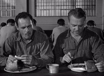 Movie still from “White Heat” (1949), directed by Raoul Walsh – A couple of men sitting at a table with plates of food; Medium shot, Low angle
