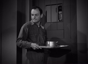 Movie still from “White Heat” (1949), directed by Raoul Walsh – A black and white photo of a man holding a tray; Medium shot, Low angle