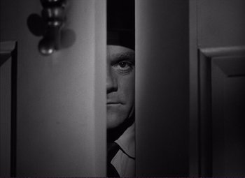 Movie still from “White Heat” (1949), directed by Raoul Walsh – A black and white photo of a man peeking through a door; Close Up shot, Low angle