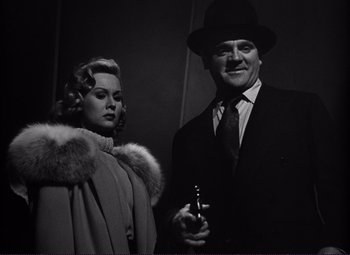 Movie still from “White Heat” (1949), directed by Raoul Walsh – A man and a woman standing next to each other holding a beer; Medium shot, Low angle
