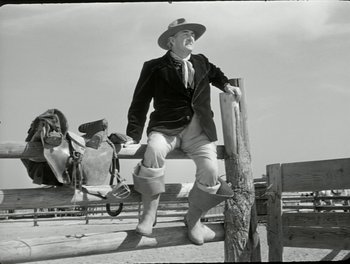 Movie still from “White Mane” (1953), directed by Albert Lamorisse – An old photo of a man standing on top of a fence; Wide shot, Low angle