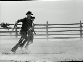 Movie still from “White Mane” (1953), directed by Albert Lamorisse – A man and a woman are running in the dirt; Wide shot, Low angle