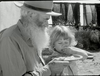 Movie still from “White Mane” (1953), directed by Albert Lamorisse – An old man and a little girl are eating food together; Close Up shot, High angle