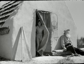 Movie still from “White Mane” (1953), directed by Albert Lamorisse – An old photo of a man and a woman sitting in front of a teepee; Wide shot, Low angle