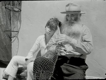 Movie still from “White Mane” (1953), directed by Albert Lamorisse – An old man and a young boy holding a fishing net; Close Up shot, High angle