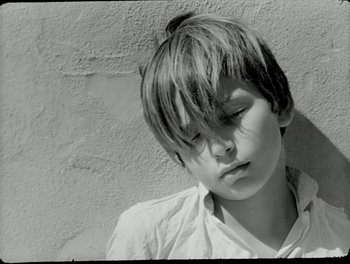 Movie still from “White Mane” (1953), directed by Albert Lamorisse – A young boy with his head tilted to the side; Close Up shot, High angle